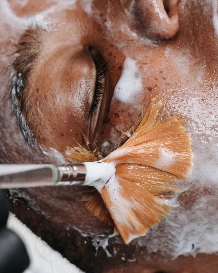 Cream cleanser being brushed across skin during a facial